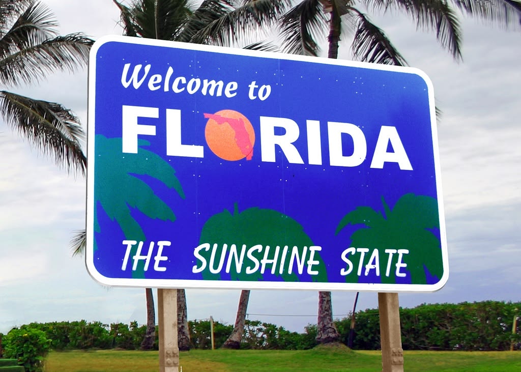 Welcome to Florida The Sunshine State road sign surrounded by palm trees
